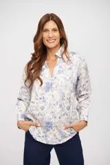 Camisa de manga larga color crema con estampado floral en tonos azules, cuello camisero y escote en V profundo.