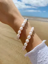 Pulsera elástica con cuentas de perlas blancas y cuentas doradas.