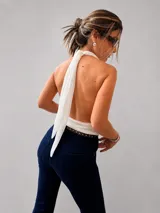 Blusa negra de gasa con escote halter y diseño drapeado frontal. Presenta un corte holgado con elástico en la cintura y espalda descubierta.