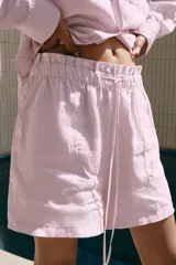 Shorts de lino de tiro medio, color rosado, con cintura elástica ajustable mediante cordones y bolsillos delanteros.