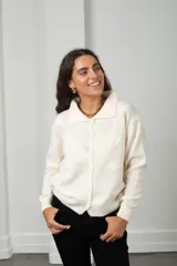 Saco de punto color blanco con cuello tipo polo, cierre frontal con botones y flores bordadas en relieve distribuidas por toda la prenda.