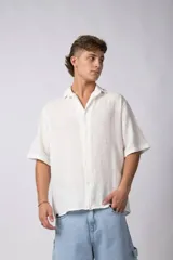 Camisa de manga corta confeccionada en una mezcla de lino y viscosa, con cuello plano y cierre frontal de botones. Presenta un diseño de calce regular con textura natural y acabado ligero.