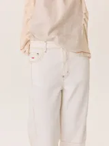 Pantalón de pana color gris oscuro, de corte barrel (holgado en caderas y muslos, ligeramente afín hacia el tobillo). Presenta costuras visibles en contraste de color amarillo claro, especialmente en la zona de la rodilla y el ruedo.