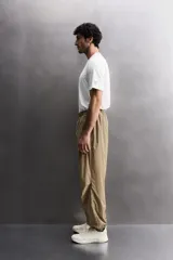 Pantalón jogger de corte regular confeccionado en tejido técnico ligero, con cintura elástica, bolsillos laterales con cierre y puños elásticos en los tobillos.