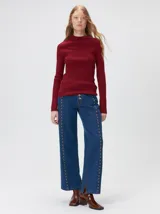 Remera de cuello alto tipo polera, confeccionada en tela rib con textura acanalada y ajuste al cuerpo. Presenta mangas largas y un pequeño bordado distintivo en la parte inferior.