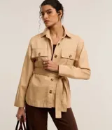 Campera trench coat color beige, con cuello inglés, manga larga, abotonado delantero, bolsillos con solapa y lazo en la cintura.