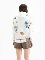 Buzo de silueta holgada y diseño rústico en color blanco, con estampado floral full print y la inscripción "LE CLUB" en el pecho. Cuenta con capucha, ojales metálicos y cordón regulable.