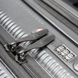 Valija de mano rígida de policarbonato color negro, modelo Londres Trip Roll de 19 pulgadas, con diseño texturizado a rayas verticales, cuatro ruedas dobles giratorias y protectores en las esquinas.