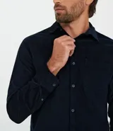 Camisa de manga larga confeccionada en terciopelo de algodón, con cuello clásico, cierre frontal de botones y bolsillo aplicado en el pecho.