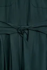 Vestido midi de estilo camisero color bordó, con cuello solapa, escote en pico y cierre frontal con botones ocultos. Presenta manga larga, bolsillos laterales ocultos, solapas decorativas en el pecho y cinturón de lazada en el mismo tejido.