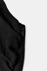 Mono largo negro con escote halter cruzado ajustable y bajo abullonado con lazada ajustable en los tobillos. Presenta un corte holgado en las piernas.