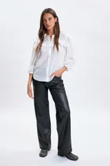 Pantalón de corte recto confeccionado en cuero sintético (PU) color negro, con cintura de tiro medio y cierre frontal.