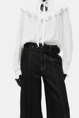 Pantalón de jean de tiro alto con pierna amplia y corte holgado. Confeccionado en denim rígido de color azul oscuro, presenta costuras decorativas verticales en el frente, bolsillos laterales y un cinturón integrado del mismo material con hebilla.