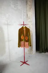 Camisa de terciopelo verde oliva con solapas largas decoradas con bordados florales en color naranja y terminaciones en flecos largos. Presenta un diseño abierto tipo kimono con mangas largas.