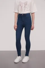 Pantalon de jean azul oscuro, corte super skinny y tiro alto, con costuras reforzadas y cierre frontal.