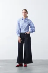 Camisa a rayas azules y blancas de manga larga, con cuello clásico y puños abotonados. Presenta un diseño entallado en la cintura.