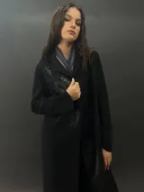 Tapado largo de paño de lana color negro con estampado abstracto brillante en el frente. Tiene cuello con solapas, bolsillos laterales y terminación al tallo vivo.