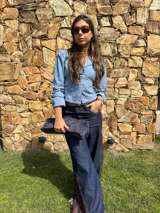 Camisa celeste con escote en V, cuello solapa y detalle cruzado con lazo ajustable en la cintura. Cuenta con mangas 3/4 abullonadas y puños con detalle de volados.