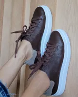 Zapatillas acordonadas de cuero color marrón con suela blanca y detalle en gamuza gris en el talón.