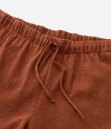 Bermuda masculina de tejido jacquard color terracota, con cintura elástica, cordón de ajuste y detalle de rayas horizontales en el ruedo.
