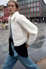 Cazadora de textura suave con cuello solapa, manga larga y cierre frontal con cremallera metálica. Presenta dos bolsillos de plastrón con solapa en la parte delantera.