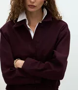 Campera bomber de sarga acanalada en color bordó, con cuello camisero, cierre frontal con botones forrados y puños con ajuste elástico.