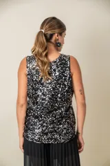 Blusa sin mangas confeccionada en tela cubierta de lentejuelas doradas y plateadas, con escote redondo y corte holgado.