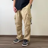 Pantalón cargo tipo parachute de color beige, con calce baggy, bolsillos laterales con solapa y cordones ajustables en los tobillos.