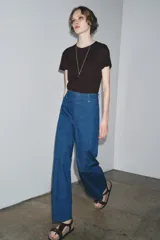 Jeans de tiro alto y pierna ancha de Zara, confeccionados en mezcla de algodón color beige. Presentan cintura con trabillas, bolsillos de parche en la espalda, costuras frontales marcadas y cierre delantero con cremallera, botón y gancho metálico.