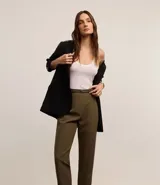 Pantalón de sastrería corte carrot, color beige, con cintura alta, pinzas frontales y cinturón fino incorporado con hebilla metálica.