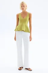 Top sin mangas de punto interlock pesado, con escote en V tanto en el frente como en la espalda. Presenta un diseño entallado con pliegues cosidos que se abren en la parte inferior creando un efecto peplum con vuelo.