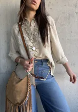 Camisa beige de manga larga con diseño bordado en el pecho, cuello camisero y cierre frontal de botones.