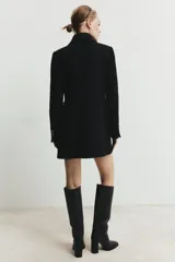 Abrigo corto de paño con mezcla de lana, cuello solapa y manga larga con hombreras. Presenta un diseño de doble botonadura con cierre frontal cruzado y falsos bolsillos de solapa en el delantero.