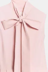 Vestido midi de Zara Woman Collection color rosado, confeccionado en hilatura de algodón. Presenta cuello subido con lazada, diseño sin mangas, bolsillos laterales ocultos y pliegues delanteros. Su falda tiene acabado en línea evasé y cuenta con cierre frontal mediante botones ocultos por solapa.