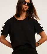 Blusa negra de crepé con cuello redondo y mangas cortas decoradas con lazos aplicados.
