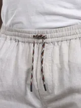Pantalón jogger color beige de lino y algodón, con cintura elástica y cordón ajustable multicolor.
