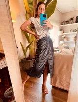 Pollera midi de cuero negro con abertura frontal y costuras blancas a contraste.