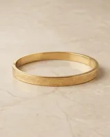 Esclava rígida de acero con baño de oro, con diseño grabado en relieve en toda su superficie.
