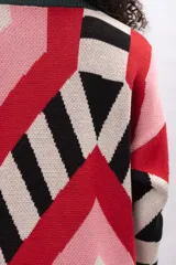 Buzo de tejido de punto con diseño geométrico multicolor en tonos rojo, rosa, negro y beige. Presenta cuello redondo y puños en color verde oscuro.