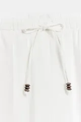 Pantalón recto de lino color verde militar, de tiro medio con cintura elástica ajustable mediante cordón y bolsillos delanteros.
