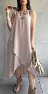 Vestido largo color beige, sin mangas, con escote redondo y corte irregular con volados.