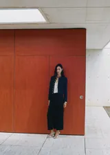 Falda midi tiro medio de color negro, con diseño cruzado y tajo delantero.