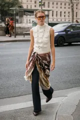 Chaleco de punto en color crudo con cuello subido y manga sisa. Presenta un diseño de tejido con estructura de cables gruesos en el frente y acabados acanalados en el cuello y el bajo.