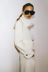 Bermuda de denim color blanco roto, tiro medio, con cinco bolsillos y bajo desflecado.