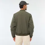 Campera estilo bomber color verde militar, con cierre frontal, cuello, puños y ruedo de tejido elástico acanalado. Presenta un bolsillo con cierre en la manga izquierda.
