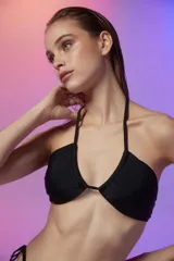 Top de bikini bandeau color negro con copas removibles y tirantes para anudar al cuello y espalda.