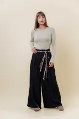 Pantalón wide leg de tiro alto en color negro, con diseño de pinzas delanteras que aportan volumen y caída fluida. Incluye bolsillos laterales y un lazo desmontable en la cintura que combina cordón con cinta de estampado animal print.