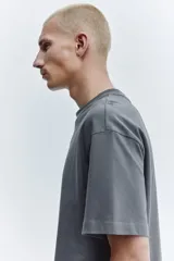 Remera de algodón de peso medio color gris, con cuello redondo ribeteado, hombros caídos, mangas cortas y corte relajado.