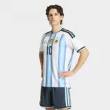 Camiseta de fútbol Adidas de la Selección Argentina, versión jugador, con el número 10 estampado. Presenta el diseño clásico de franjas verticales celestes y blancas, con detalles en negro en los hombros y cuello. Incluye el escudo de la AFA con tres estrellas y el parche de campeón mundial FIFA.