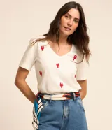 Blusa de manga corta color blanco crudo, confeccionada en tejido flamé de algodón, con escote en V y delicados bordados de langostas rojas distribuidas en el frente.